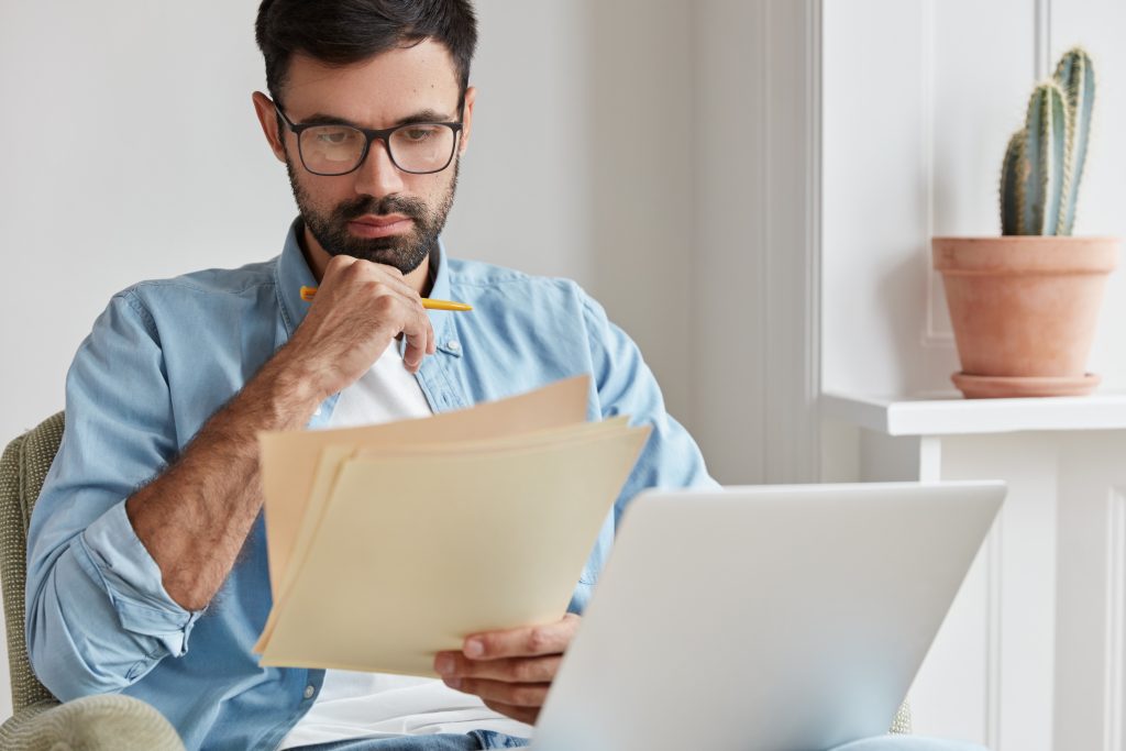 profesional leyendo atentamente, y sosteniendo unos documentos. Errores financieros que debes evitar